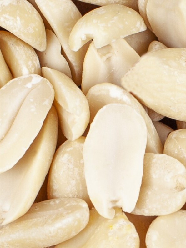 A wooden board full of peeled almonds
